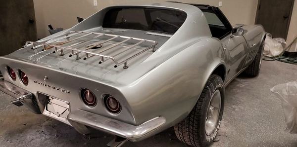 Rear view of a classic sports car refinished in silver, chrome luggage rack on the deck