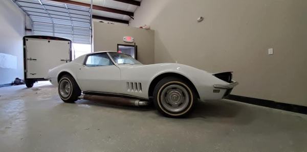 Classic sports car refinished in white, side view in the shop