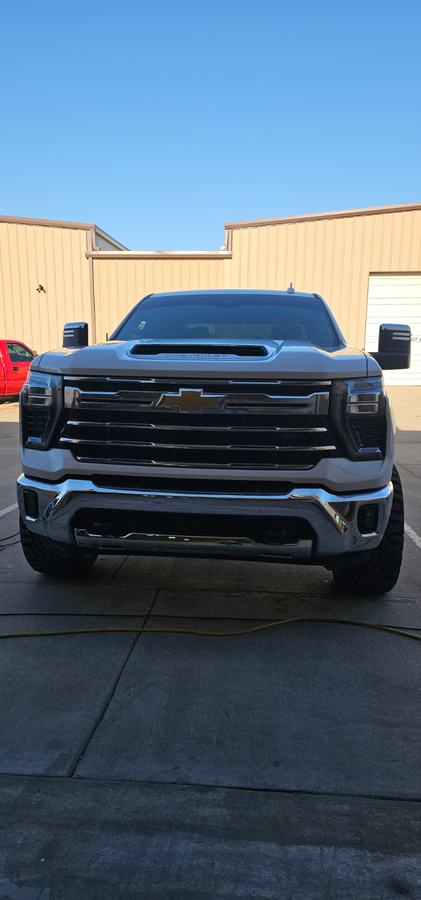 Front view of a heavy-duty pickup after front-end repair, parked outside the shop