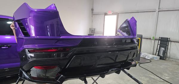 Purple and carbon rear bumper assembly on a stand in the shop