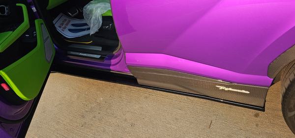 Close-up of a carbon fiber side skirt under a purple door