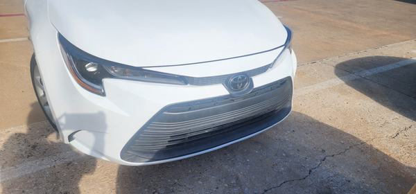 White sedan front bumper and hood after repair and refinish, straight-on view