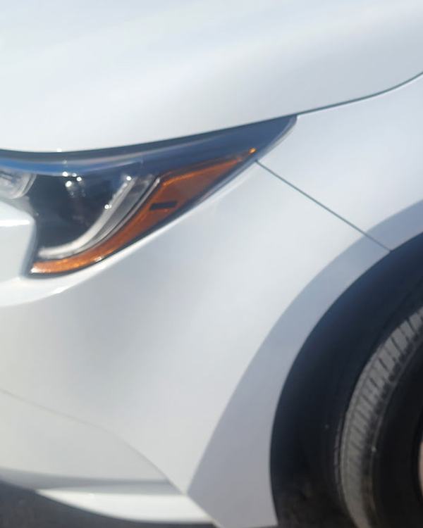 After: white sedan front bumper and fender, repaired